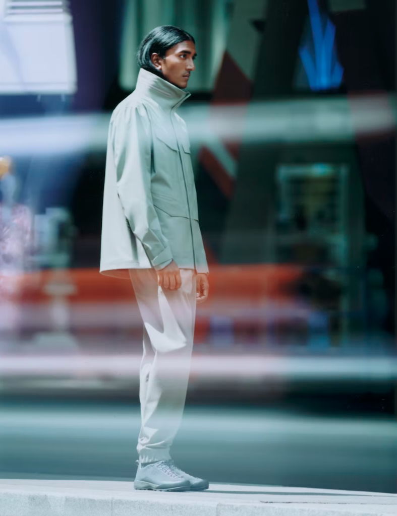 A man looking off to the side in a futuristic Arc-teryx Veilance grey jacket with matching pants and shoes