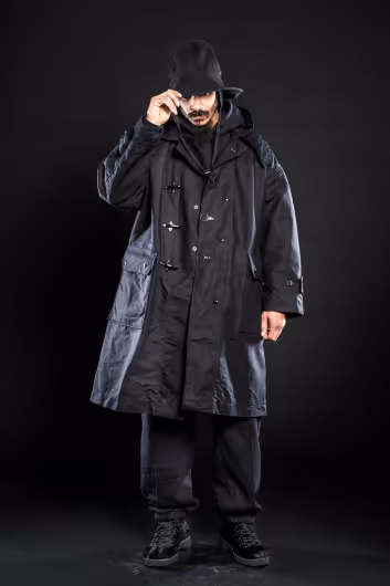 A man wearing all black including an Engineered Garments jacket, bucket hat, and pants.