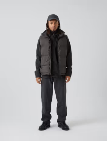 A man with dreads wearing a grey puffy Mads Norgaard vest and a matching hoodie, pants and hat.