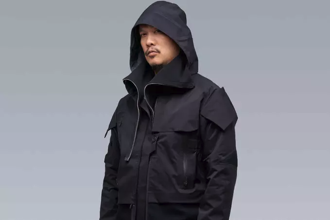 A man wearing a black Acronym jacket with his hood on