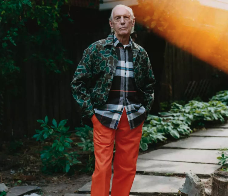 An older man wearing a camo print Noah jacket and orange pants