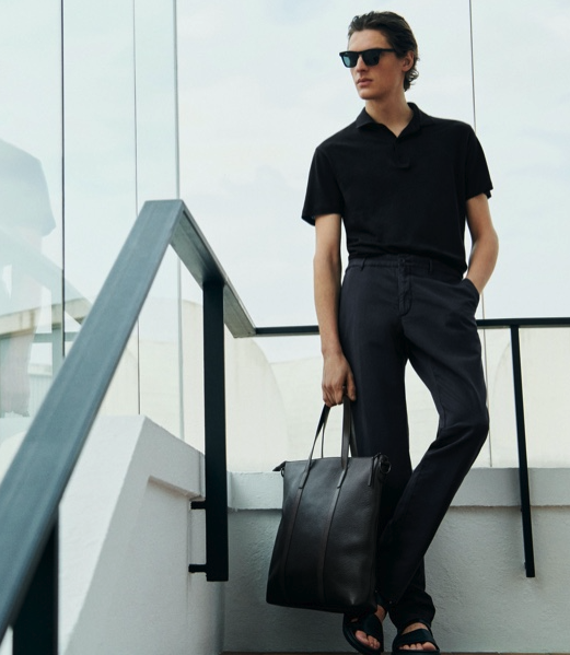 A young man with slicked back hair wearing a short-sleeve Massimo Dutti shirt, dress pants and a matching leather bag