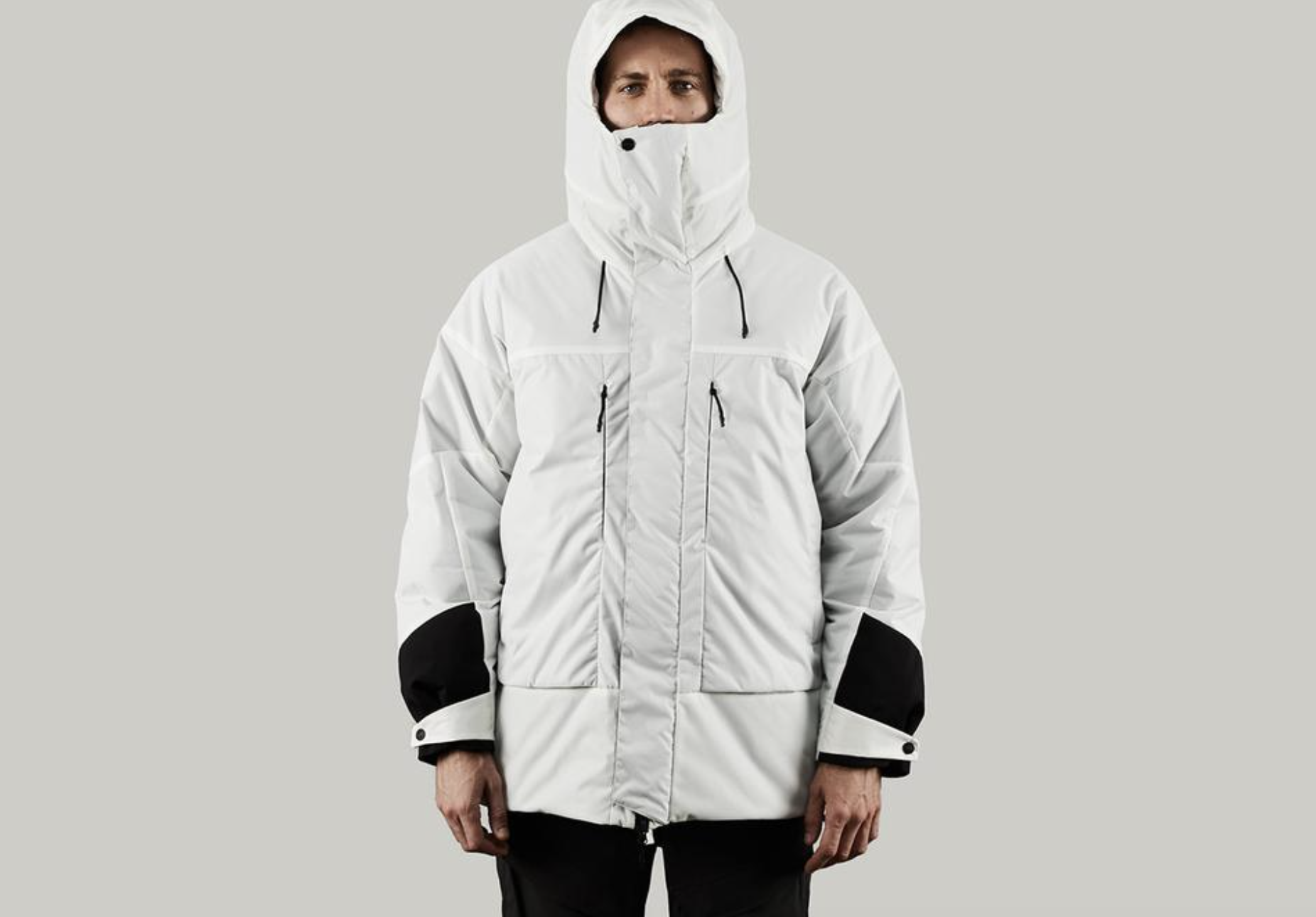 A man in a photoshoot setting wearing a white futuristic looking Vollebak Jacket