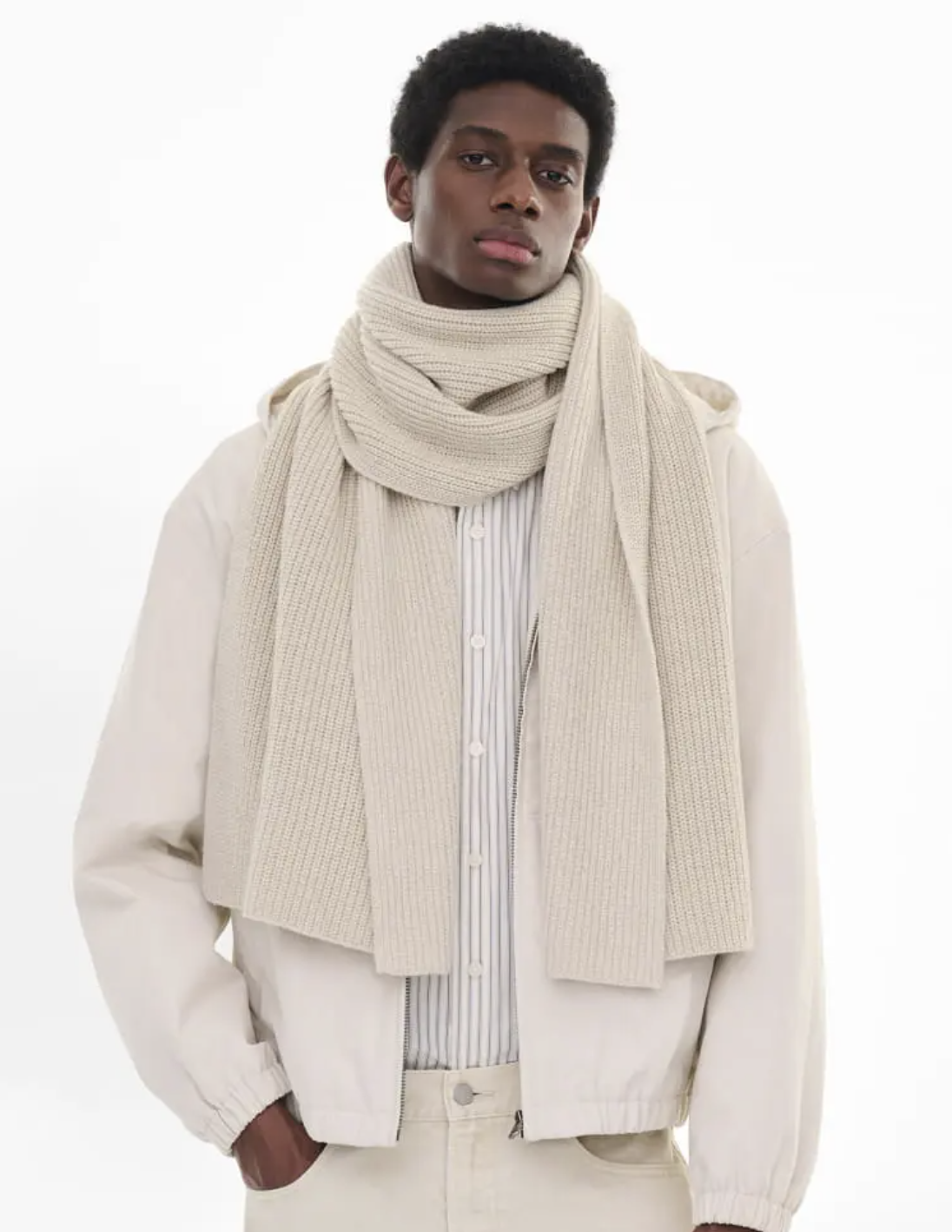 A man wearing an oversize Uniqlo beige scarf with a striped button up and a beige coat