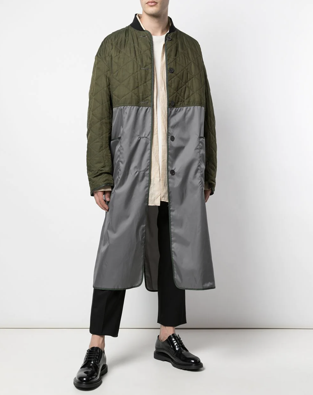 A man wearing a green Haider Ackermann trench coat with black pants and shoes