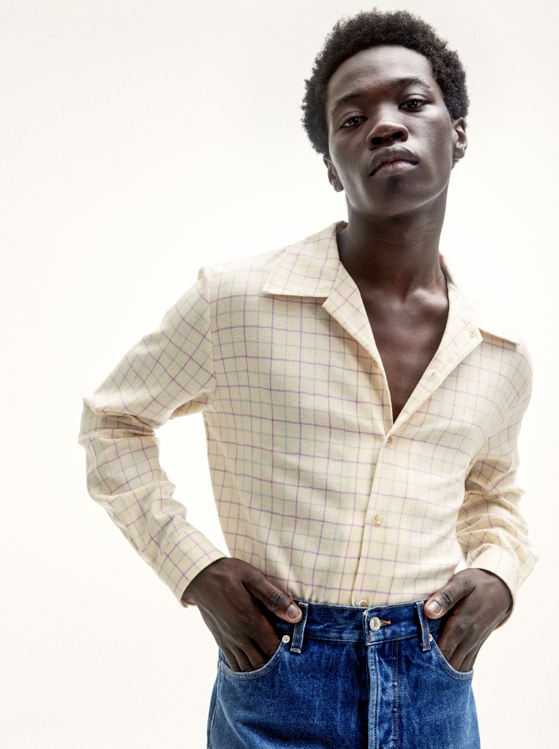 A man wearing Sefr jeans and a yellow striped long-sleeve button-up