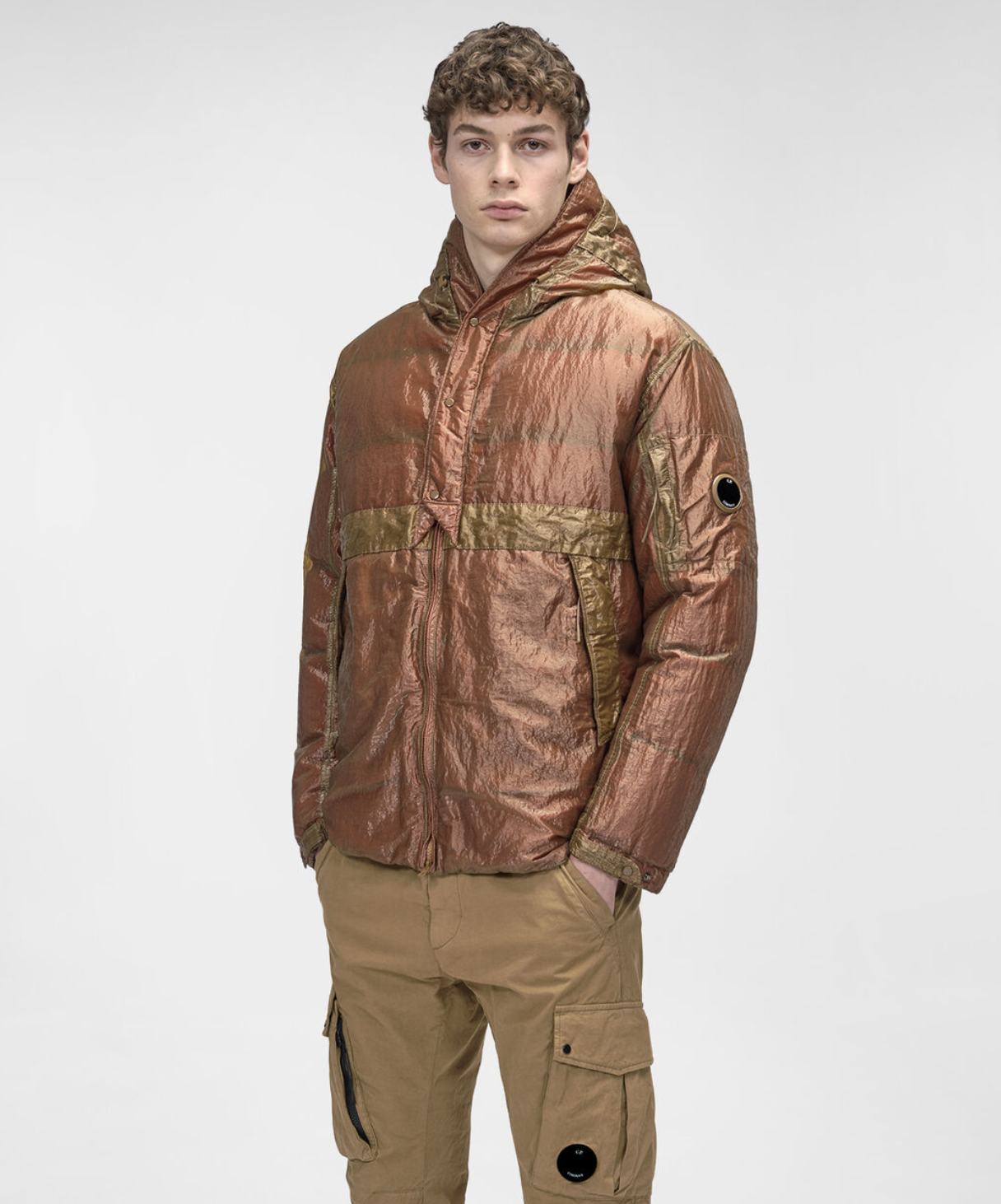 A man wearing a CP Company red and brown technical jacket and brown pants