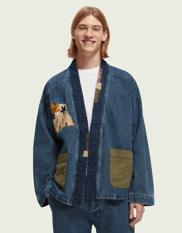 A man wearing a Scotch & Soda Japanese style denim jacket and matching pants with floral designs sewn on