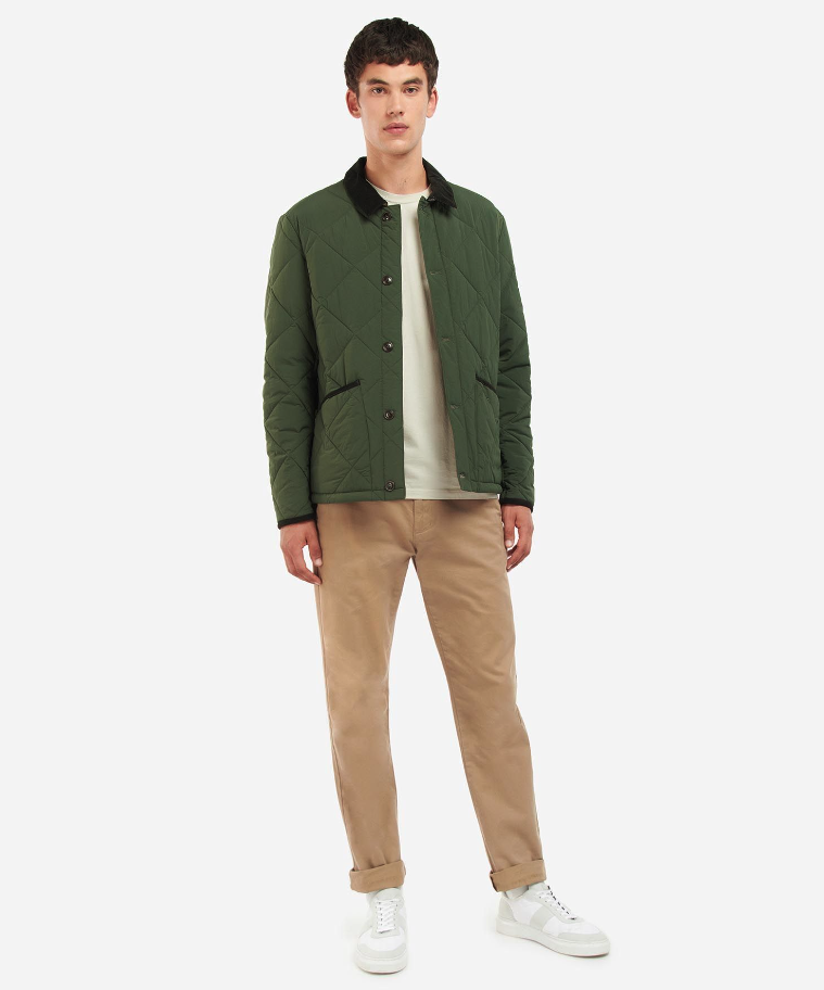 A man wearing a Barbour green jacket, a cream t-shirt and brown pants