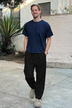 A man walking while wearing Outdoor Voices navy blue shirt and black pants