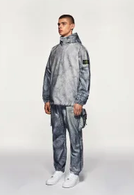 A man wearing a Stone Island futuristic looking tracksuit with white shoes
