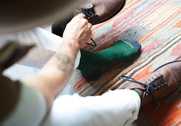 A man putting on a green Wigwam wool sock