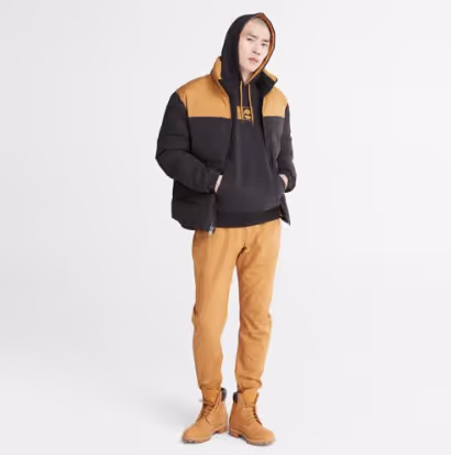 A man wearing a timberland outfit with a brown jacket, pants and boots