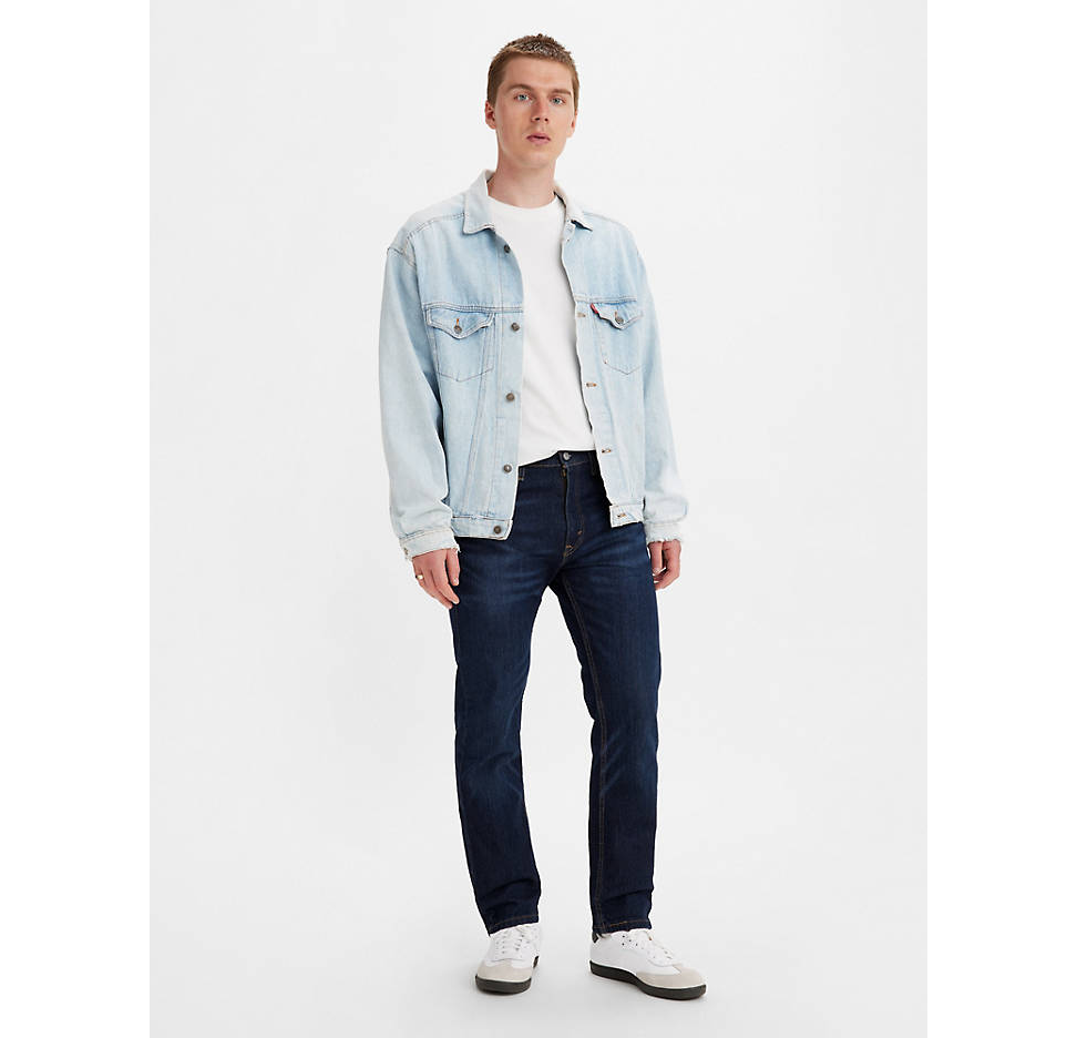 A man wearing a denim Levis jacket, white t-shirt and black pants