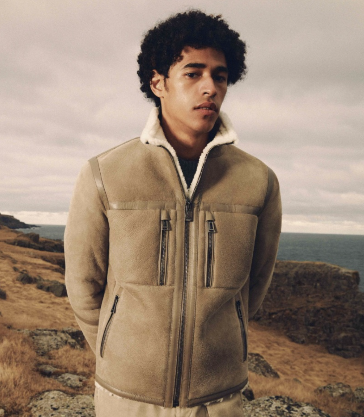A man wearing a Belstaff sheepskin jacket with khaki pants