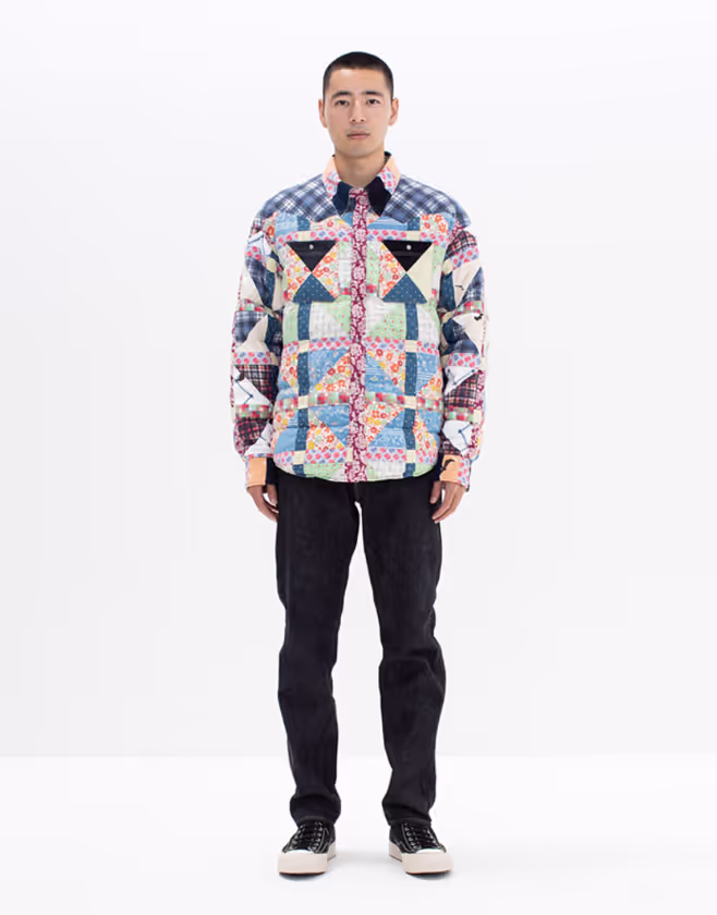 A man wearing a colorful Vivsim button up with black pants and black sneakers