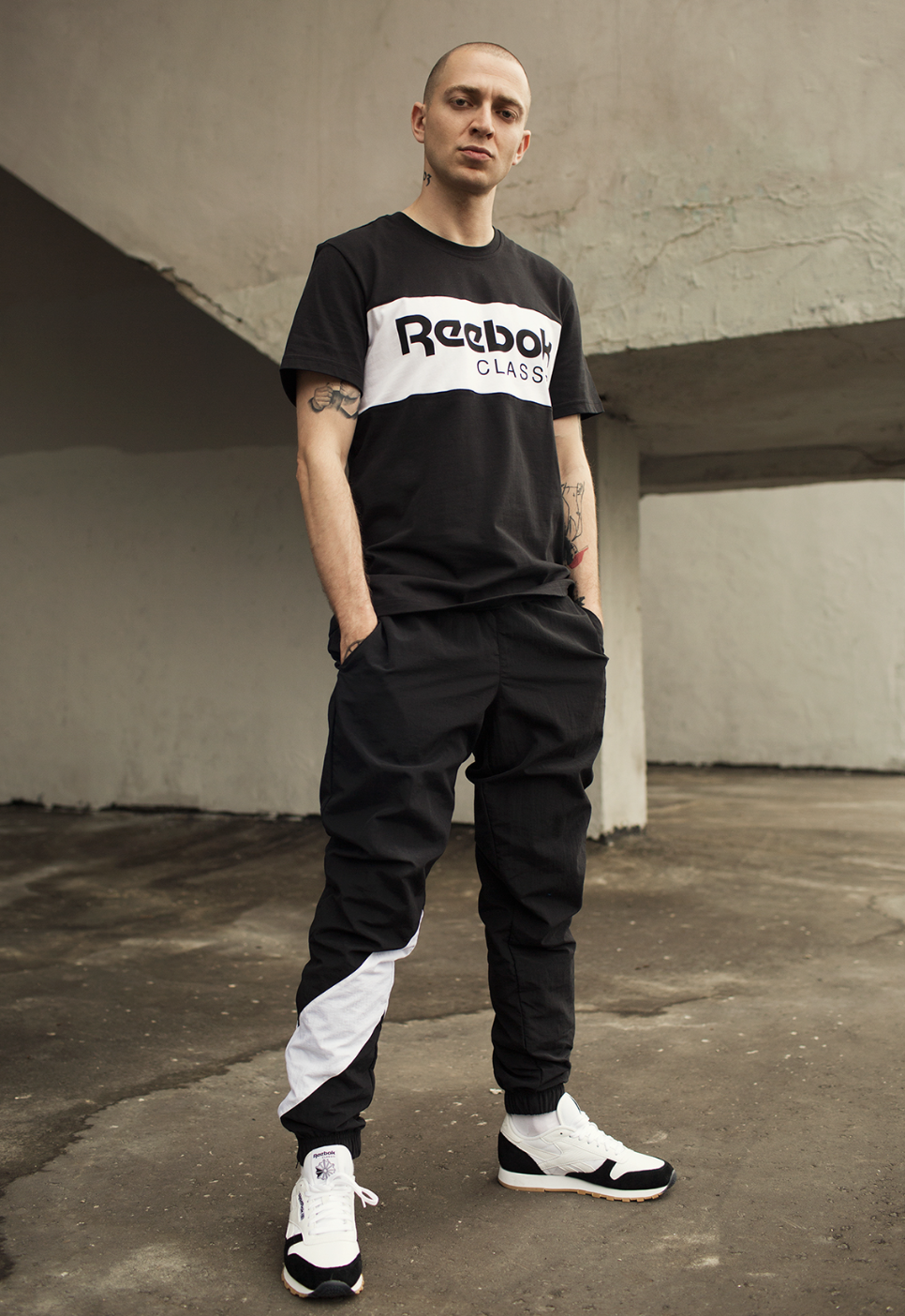 A man standing wearing a black and white Reebok Classics outfit with matching sneakers