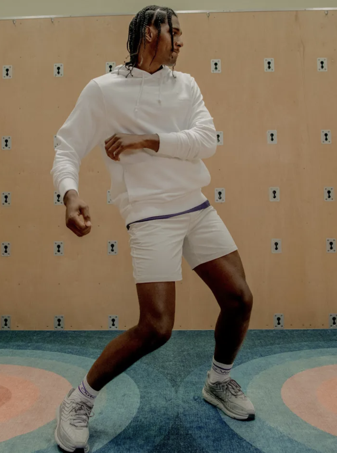 A man wearing a Outdoor Voices white hoodie, short shorts and matching socks