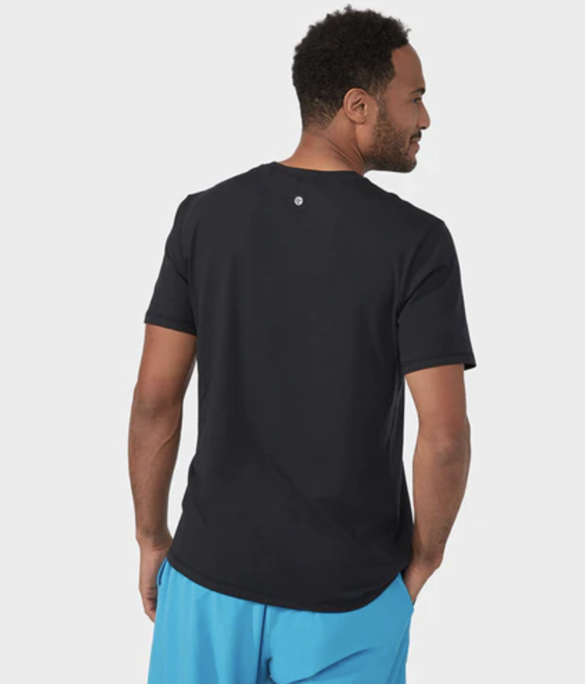 A man wearing a Manduka athletic outfit with a black shirt and bright blue pants