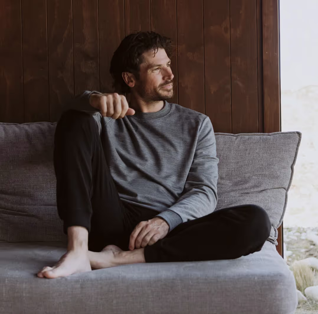 A man sitting in an Icebreaker grey sweatshirt and black pants