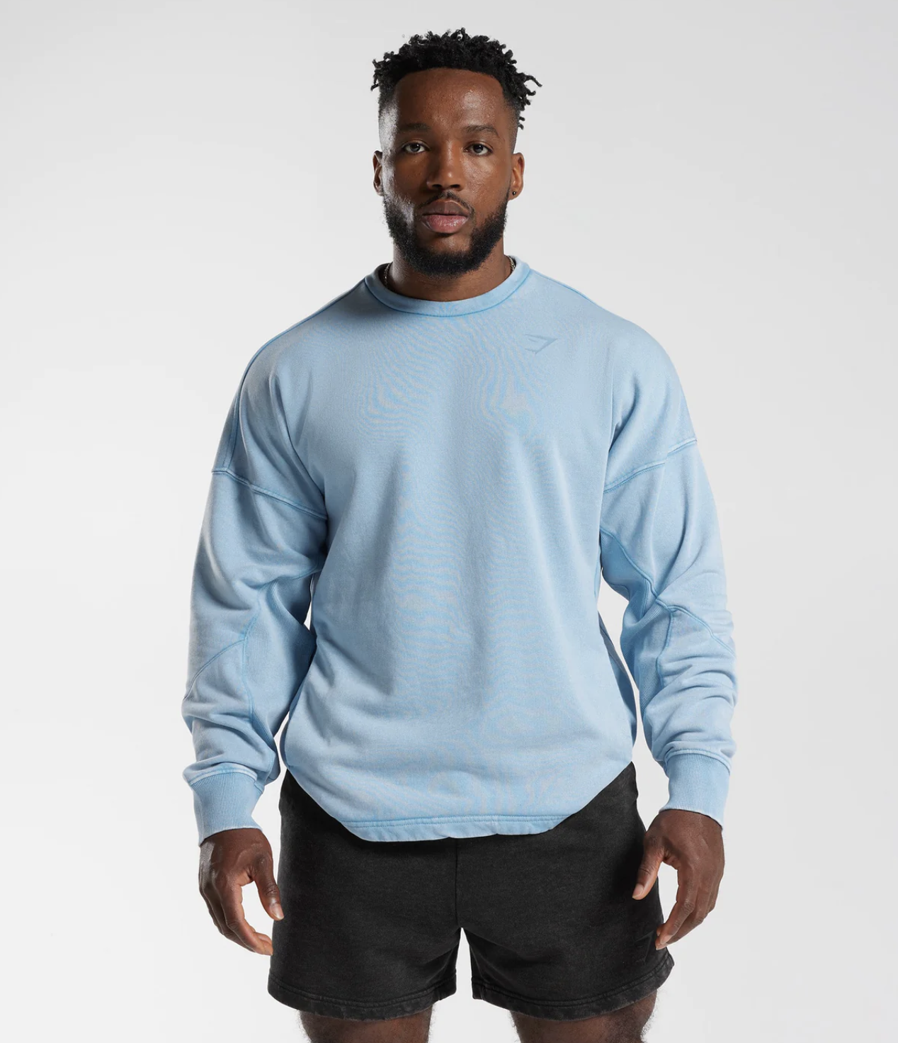 A man wearing a baby blue Gymshark sweatshirt and short black shorts