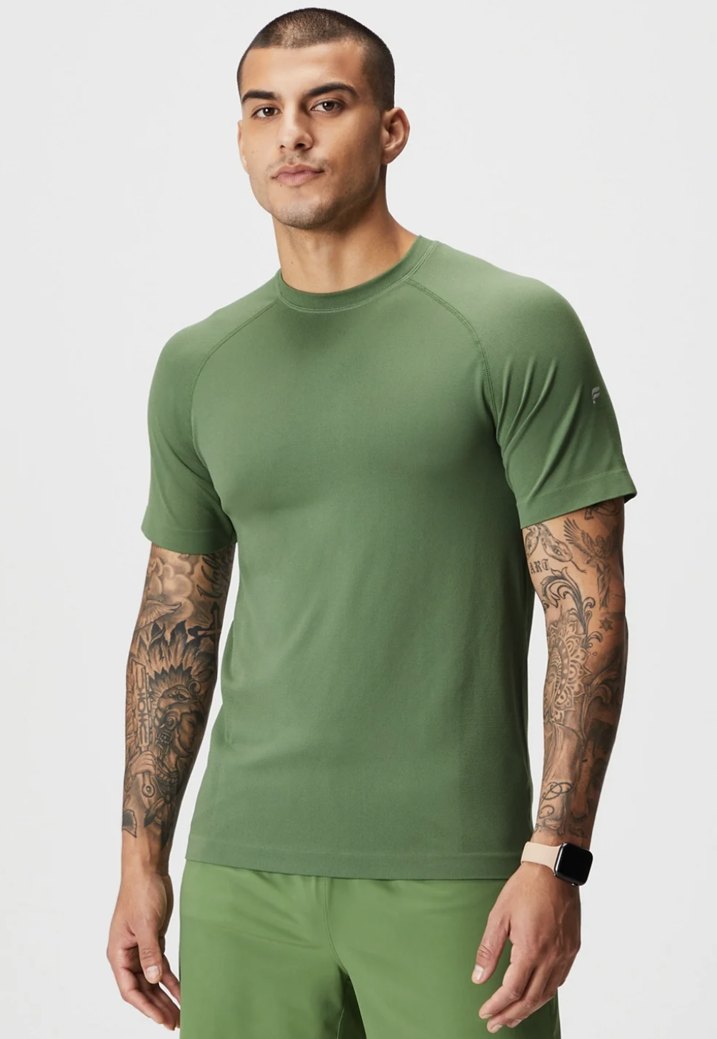 A man wearing a tight-fitting green Fabletics athletic shirt and pants