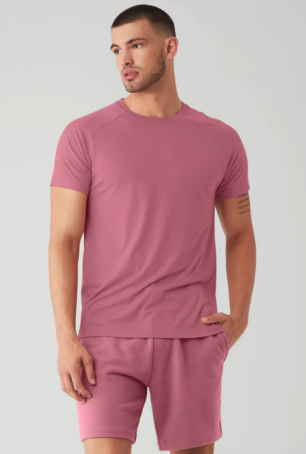A man wearing a red Alo Yoga t-shirt and matching yoga shorts