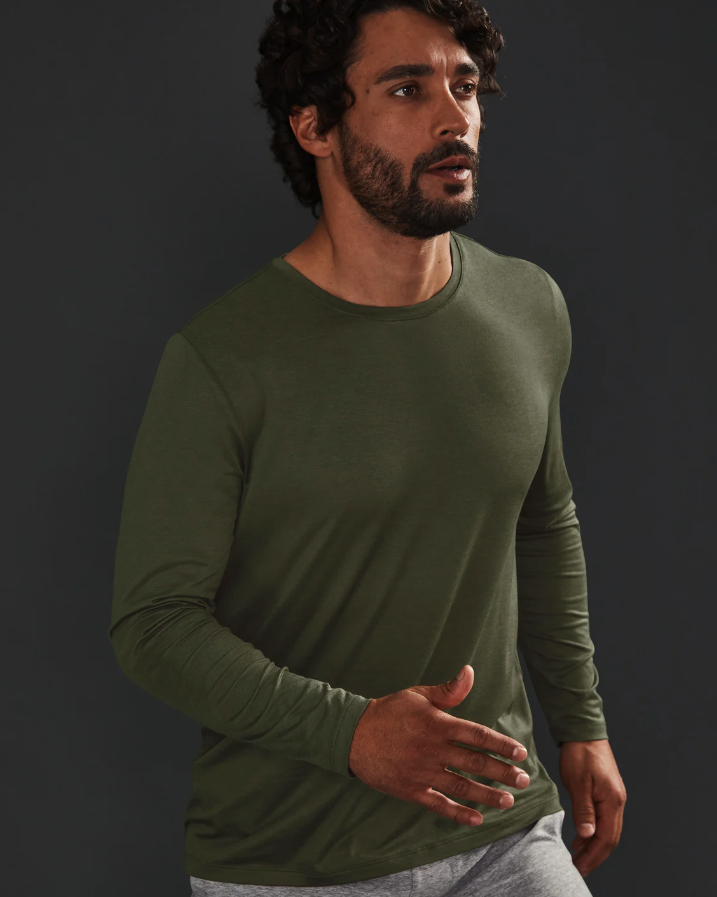 A man wearing a tight-fitting green Beyond Yoga athletic long-sleeve