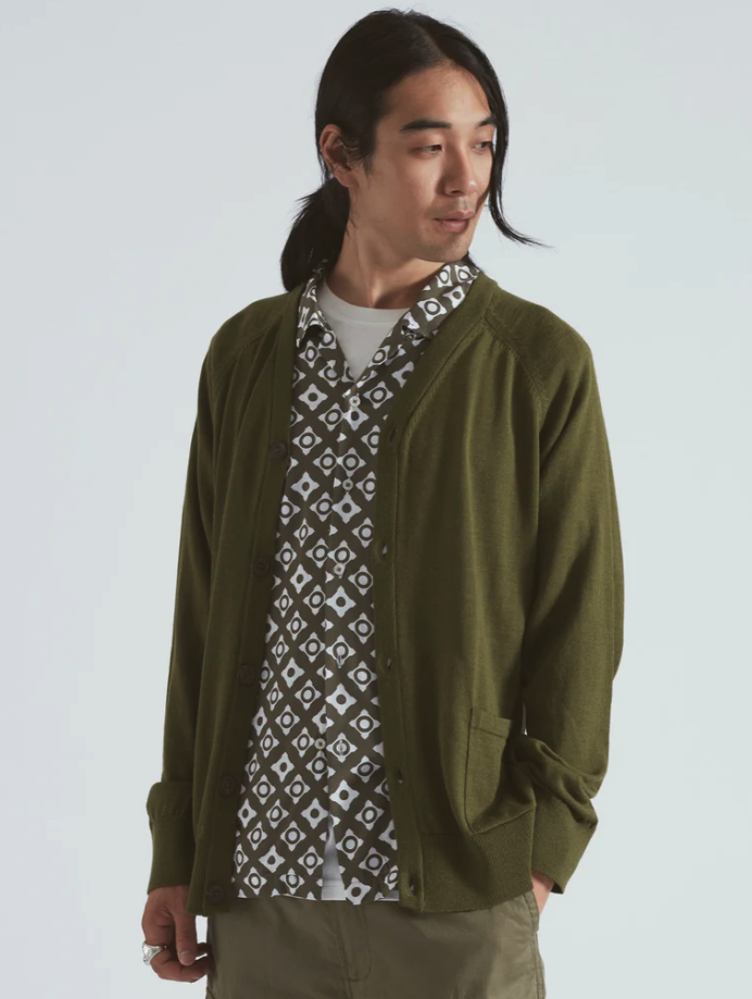 A man wearing a Universal Works green cardigan with a green patterned button up underneath