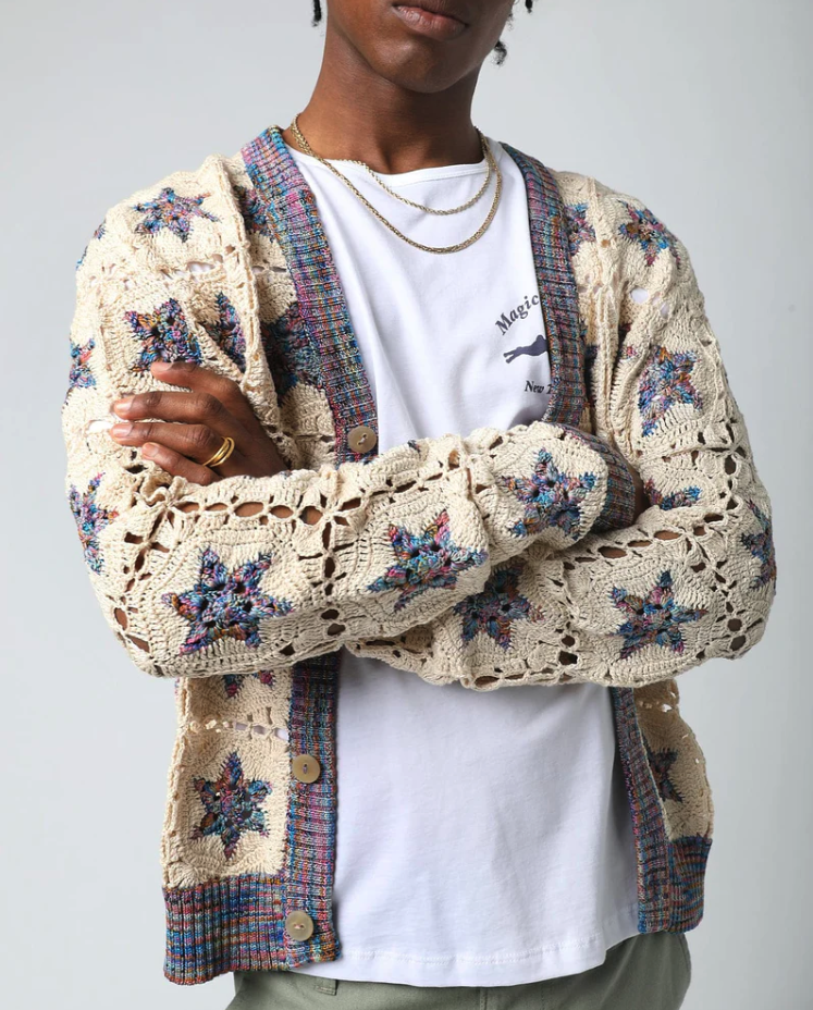 A man wearing a Corridor knitted and colorful cardigan with a white t-shirt underneath