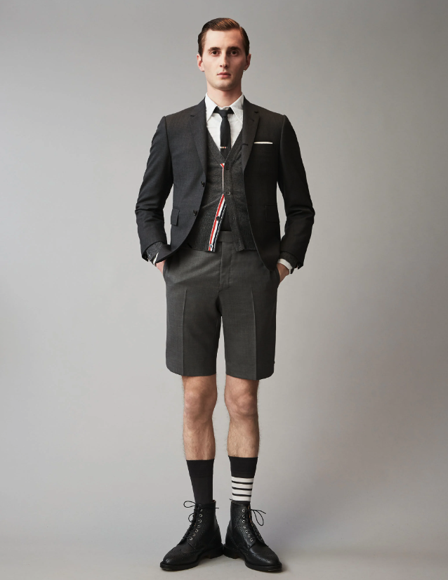 A man wearing a Thom Browne short suit with high socks and dress shoes