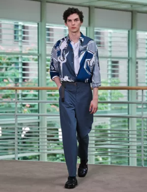 A man wearing a blue Hermes button up with blue pants