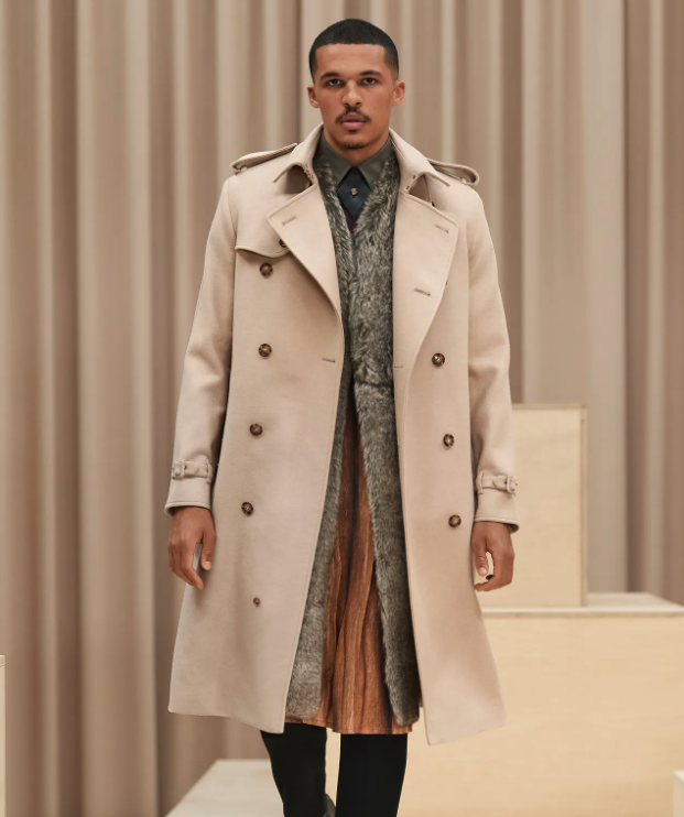 A man wearing a light brown Burberry trench coat with a large floral jacket underneath