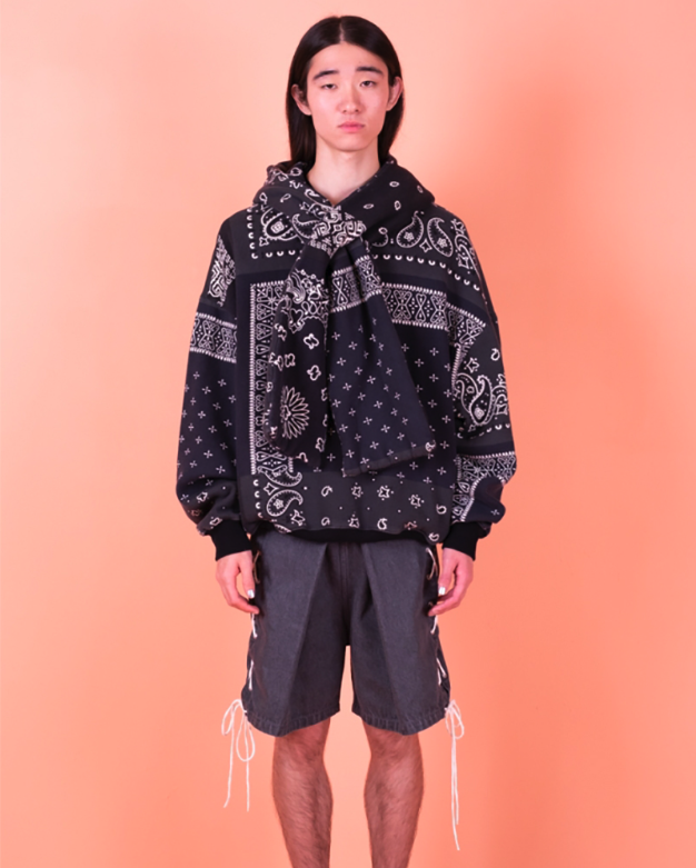 A man wearing a Kapital jacket with a black bandana print and shorts