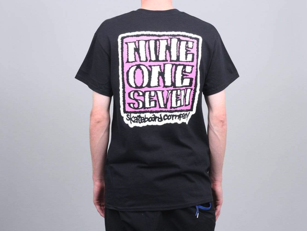 A man wearing a Call Me 917 t-shirt with a large print on the back in pink and white