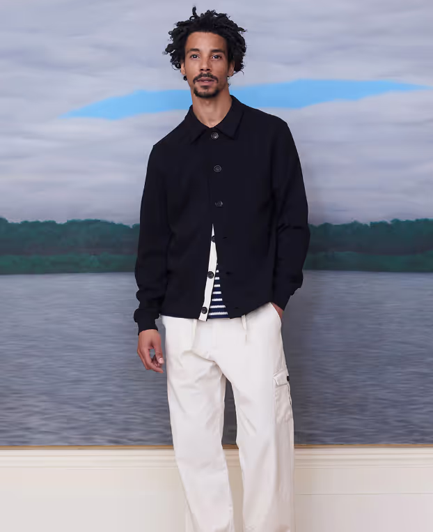 A man wearing a Oliver Spencer black jacket with beige pants