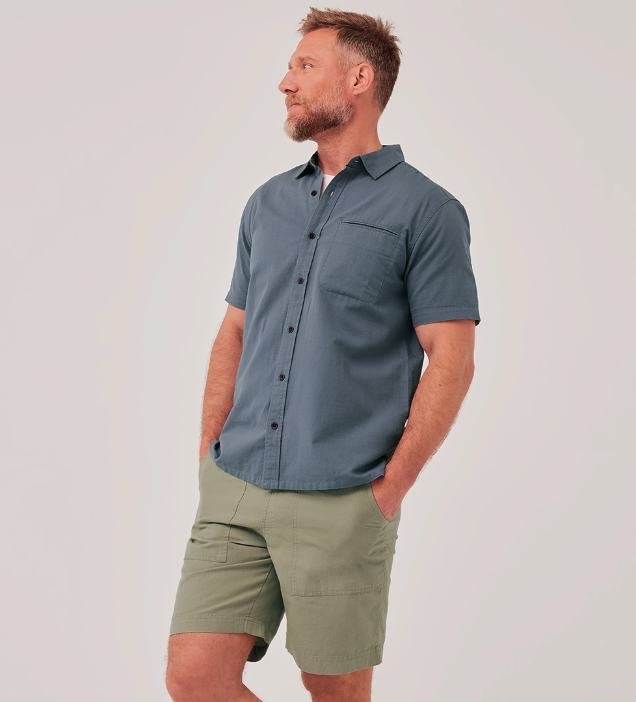 A man wearing a grey short-sleeve Pact shirt and light green shorts