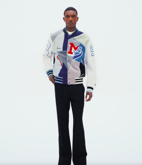 A man wearing an Amiri coaches jacket with black pants