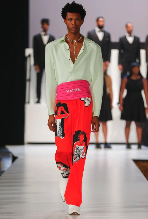 A man walking a runway wearing a avante-garde and colorful outfit from Pyer Moss