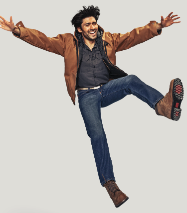 A man jumping in a brown Red Kap jacket and work boots