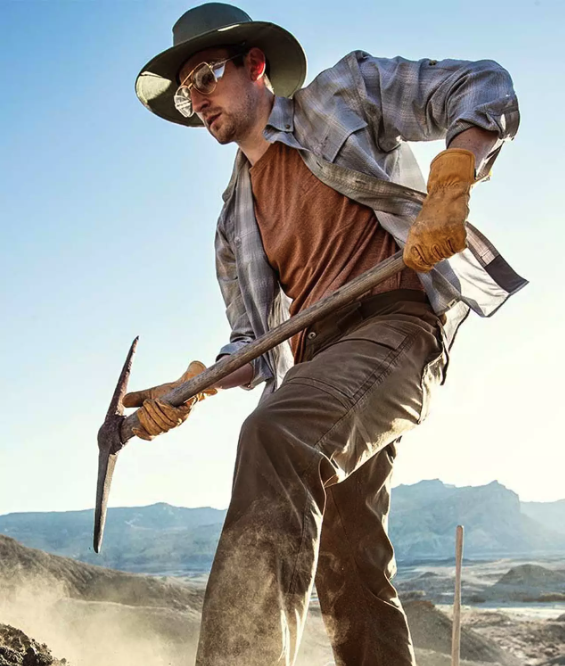 A man working with a pickaxe wearing Duluth Trading Co. workwear