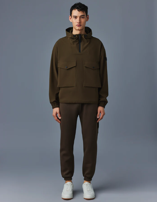 A man wearing a Mackage winter coat in olve green with sweatpants and white shoes