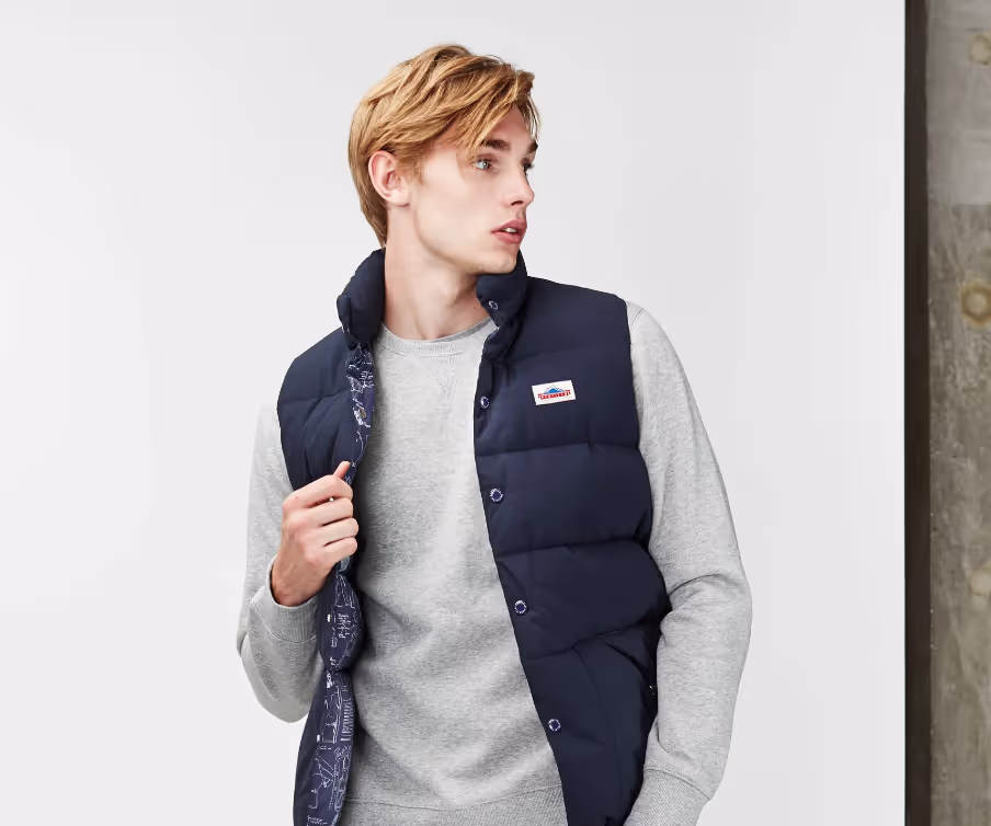 A man wearing a grey sweatshirt and a navy blue penfield vest