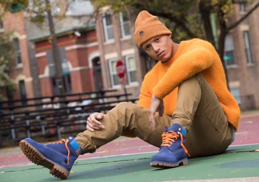 A man sitting on a basketball court wearing blue timberland boots