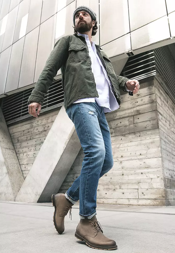 A close up of a man wearing brown Frye boots