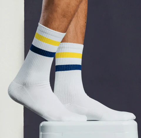 A close up of a Pair of Thieves white socks with a yellow and blue stripe