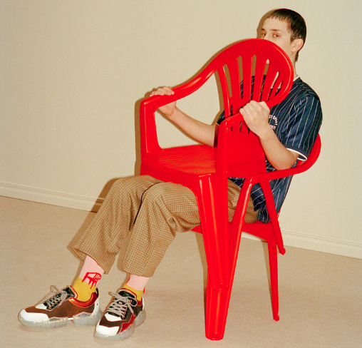 A man sitting wearing socks with a red lawn chair design on them