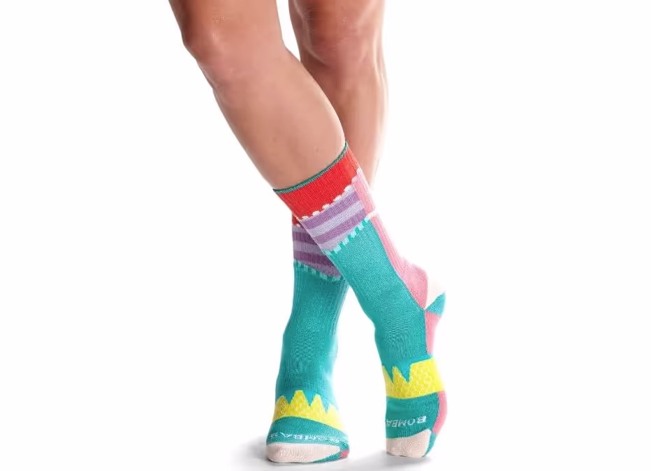A close up of a colorful pair of bombas socks on feet