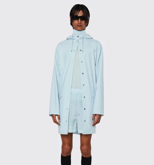 A man wearing a baby blue Rains raincoat with matching shorts and black sunglasses