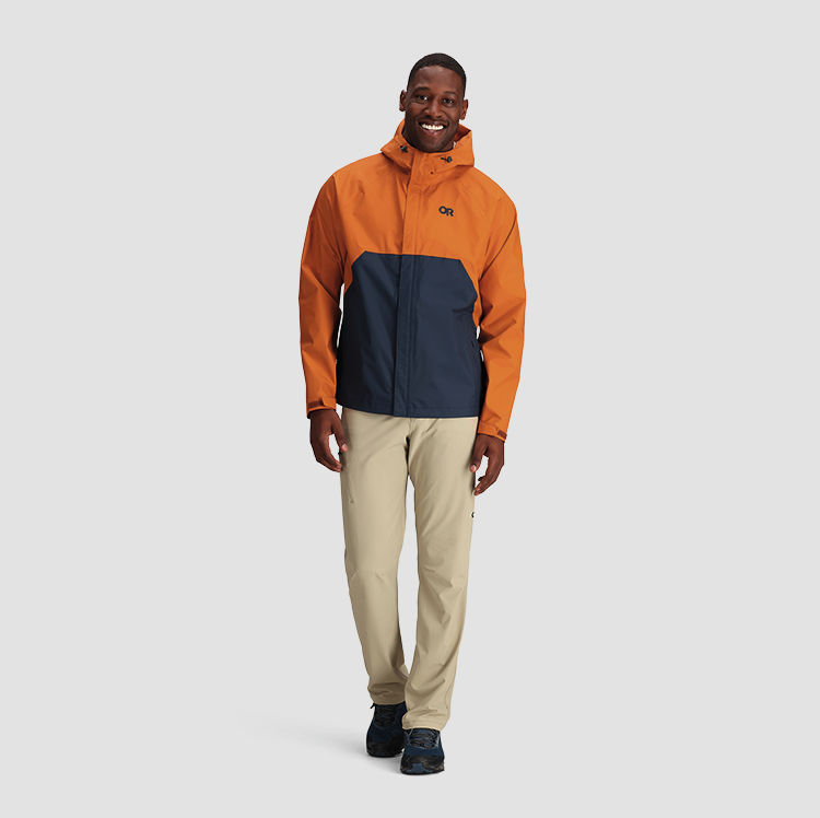 A man wearing an orange and navy blue Outdoor Research Jacket and beige pants